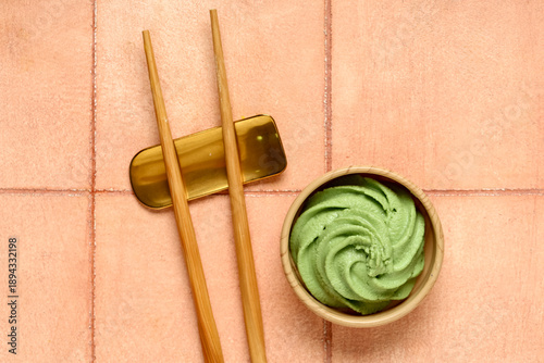 Konstfotografi Bowl with wasabi paste and chopsticks on beige tile background