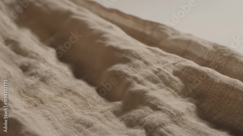 Close-up of textured fabric with folds and shadows, neutral tones.