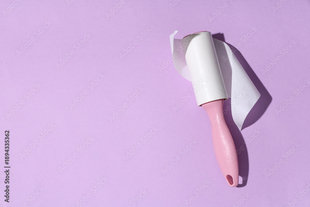 Fototapeta premium Sticky lint roller on lilac background