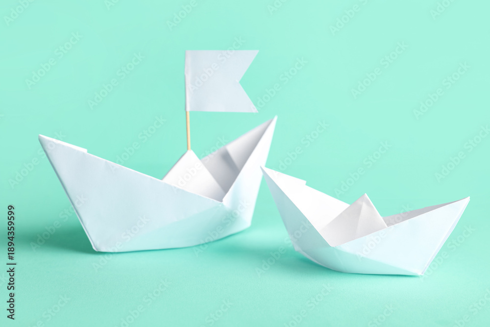 Naklejka premium White paper boats with flag on turquoise background