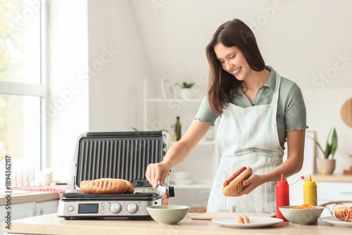 Young woman cooking hot dog...