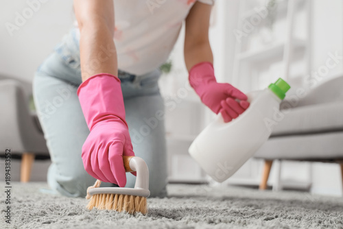 Young woman cleaning carpet...