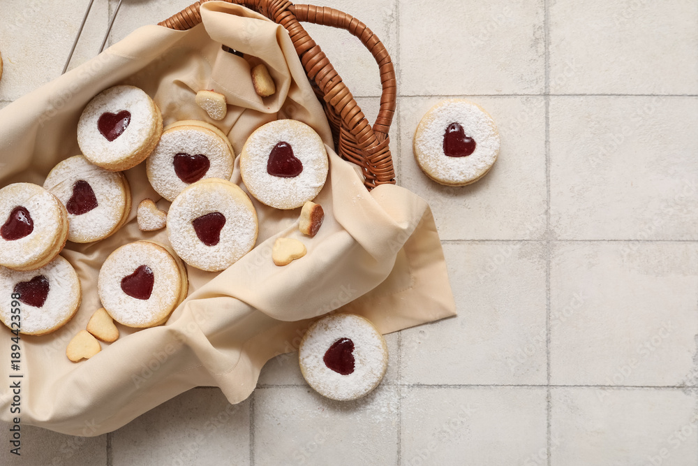 Fototapeta premium Wicker basket with sweet cookies on white tile background. Valentine's Day celebration