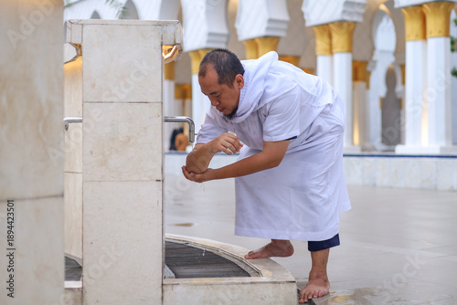 Canvas Print Religious Man Wearing White Clothes Performing Ablution At Outdoor Station In Mo