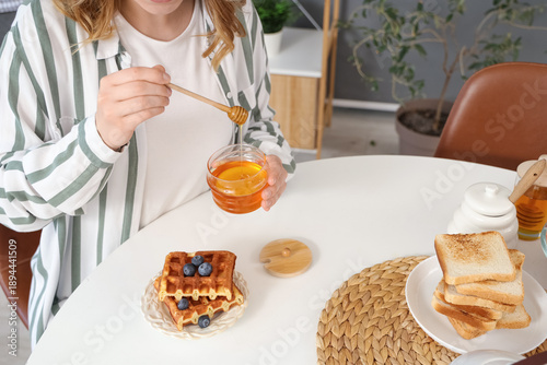 Woman adding sweet honey to...