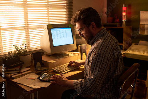 Quadro em tela Caucasian man working at desk using vintage computer and calculator, focusing on