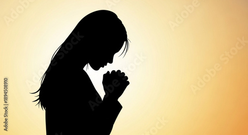 Woman praying silhouette with clasped hands against warm golden background