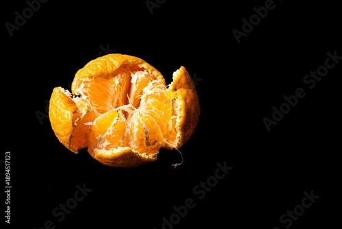 Peeled tangerine fruit on a black background, macro shot