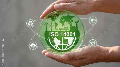Hands holding green globe with ISO 14001 and eco-friendly symbols