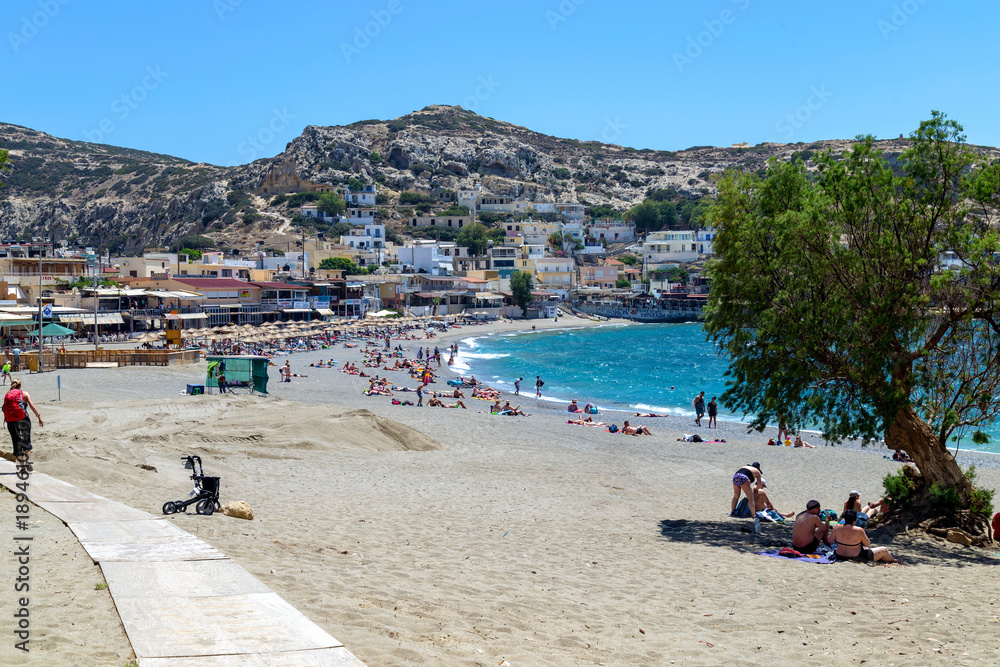 Fototapeta premium Sunny Beach of Matala Bay with Tourists – Summer Holiday on Crete, Greece