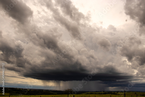 Foto Dramatic cumulonimbus storm cloud forming over a rural landscape, with rain falling in a visible curtain in Brazil