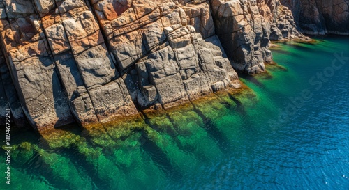Rugged coastal rim adorned with captivating geological strata, merging seamlessly into the tranquil, azure waters below