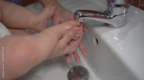 10.10.2025 UAE. Dubai.Mom washes little boy's feet under the faucet.