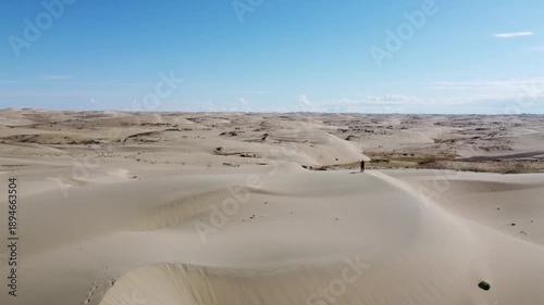 People walking through the desert, aerial photography, view of the dunes from above

