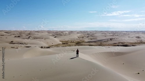 People walking through the desert, aerial photography, view of the dunes from above

