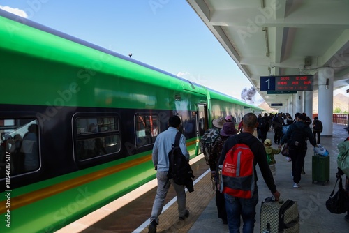 Passengers board a green train on the Lhasa-Shigatse railway at Shigatse Railway Station, Tibet, highlighting high-altitude rail travel, tourism, and modern transportation in western China.