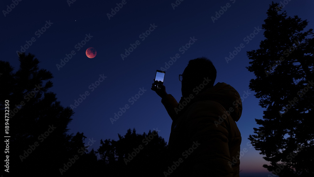 Fototapeta premium Amateur astronomer with smartphone photographing and observing stars, planets, Moon and other celestial objects.