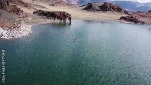 flying a quadcopter over the lake. A girl on a snowboard swims on a lake
