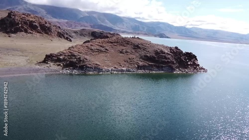 flying a quadcopter over the lake. A girl on a snowboard swims on a lake
