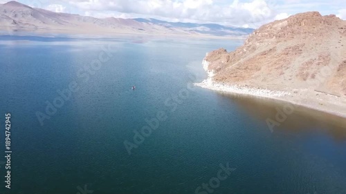 flying a quadcopter over the lake. A girl on a snowboard swims on a lake
