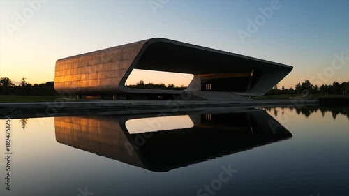 Modern architectural structure reflected in still water at sunset