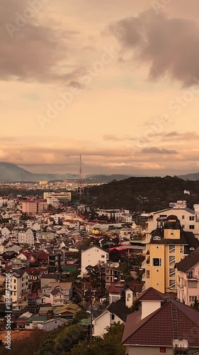 Aerial panorama of Da Lat city in Vietnam during twilight with sunset sky. Wide urban landscape showing rooftops, streets, and mountain surroundings
