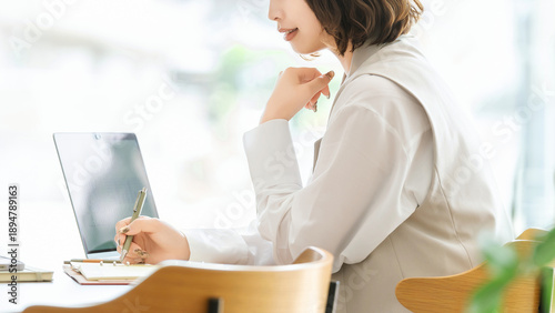 Bild auf Leinwand ノートパソコンを使いながらメモを書くビジネスウーマン, Businesswoman Writing Notes While Using Laptop
