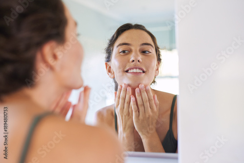 Beautiful mid adult woman checking skin at mirror