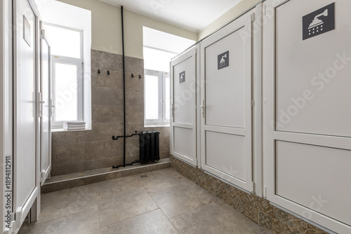 Obraz na plátně Row of modern white shower cabins in a shared hostel bathroom