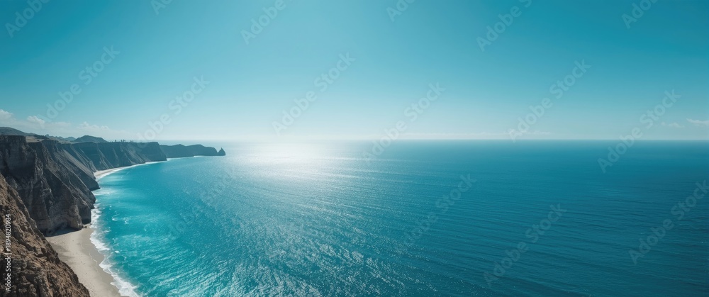Obraz premium A stunning scene of the blue ocean along the rugged coastline, set against a wide sky and untouched beach, illustrating nature's landscape charm