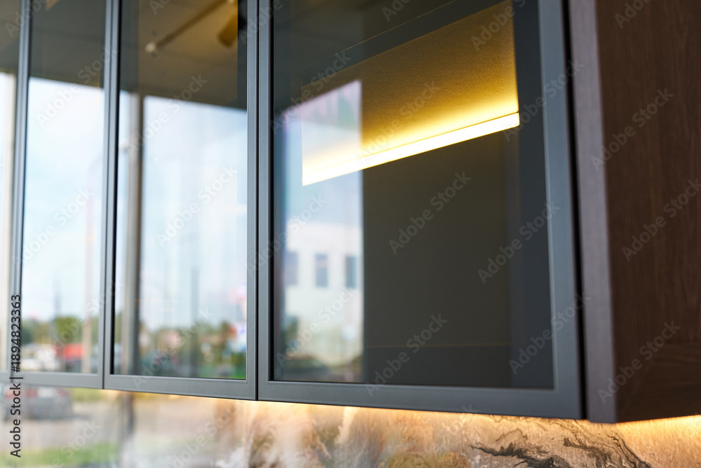 Fototapeta premium Modern kitchen cabinets with glass fronts, aluminum frames and lighting.