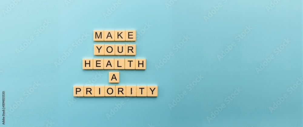Naklejka premium Wooden blocks spelling Make your health a Priority next to a Health symbol on a Beautiful blue background. Health concept. Copy space