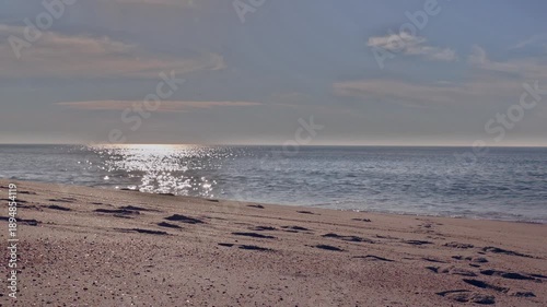 Sunny Atlantic beach with calm sea and footprints in sand under clear sky, Portugal, Praia da Gaivinia, 13 October 2025