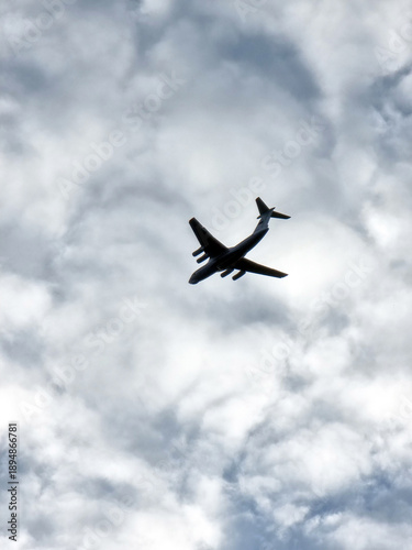фотографія Airplane silhouette flying through cloudy sky