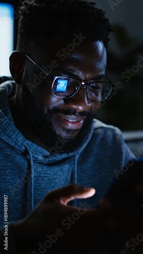 Man using smart phone indoors at night illuminated by screen