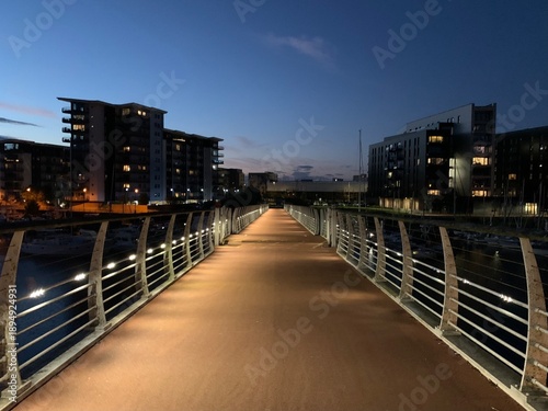 Illuminated pedestrian Pont y Werin bridge between Penarth and Cardiff at dusk, Wales, United Kingdom, July 2022
