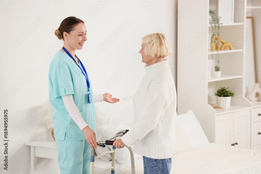 Fototapeta premium Caregiver and senior woman with walker in nursing home