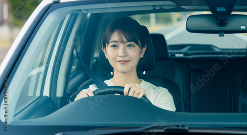 フロントガラス越しに微笑みながら安全運転する若い日本人女性