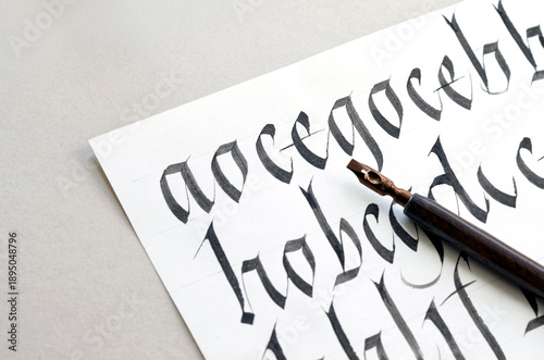 Letters, calligraphy ink pen, paper. Learning calligraphy lettering