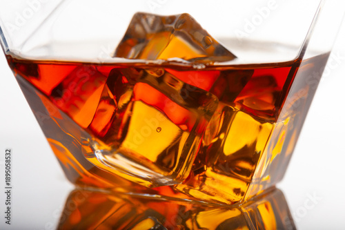 Close up of whiskey glass with ice cubes, amber liquor texture, premium alcohol drink, luxury bar concept, crystal glass reflections, warm tones, studio macro still life photography