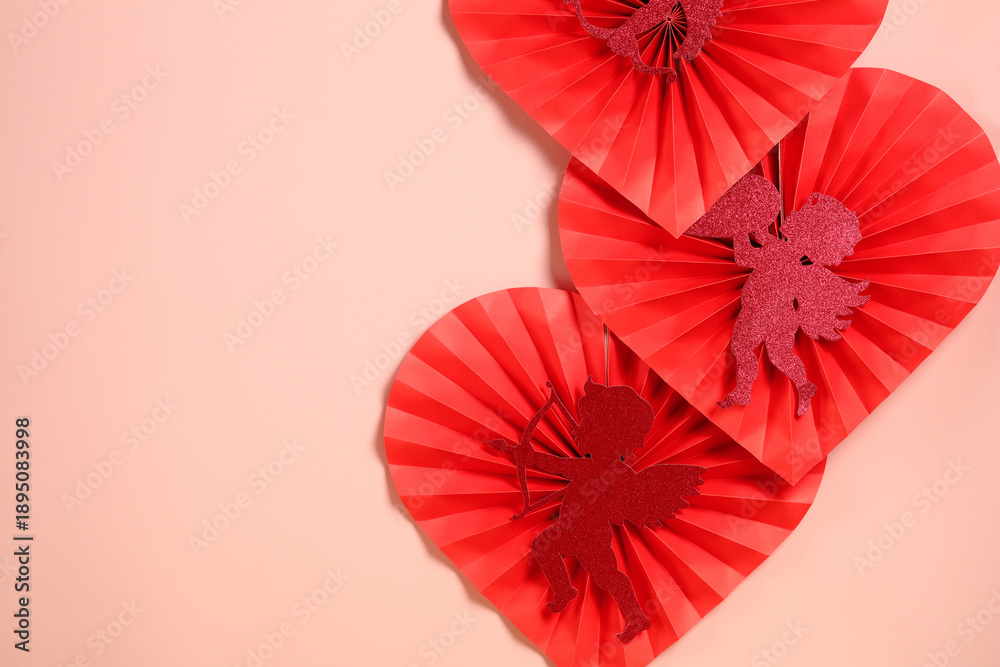Fototapeta premium Red paper hearts with glitter cupids arranged on pink background with copy space