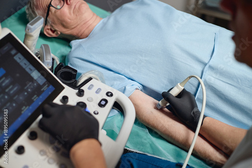 Foto Senior Caucasian man lying on hospital bed undergoing vascular ultrasound examin