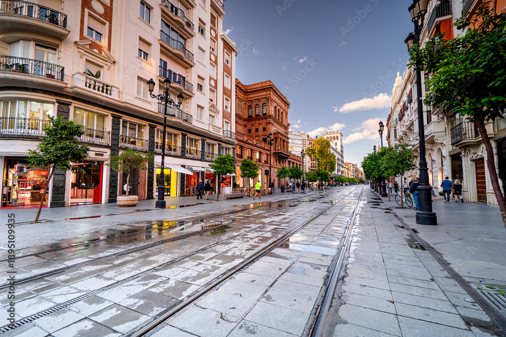 Naklejka premium Main Street in Seville with colorful houses and people, life on the streets of the Spanish city, Andalusia.