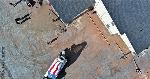 Aerial view of construction site with workers, heavy machinery, cement mixed vehicle featuring US patriotic design.
