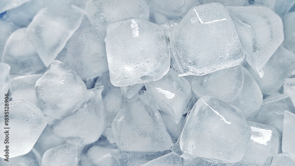 Obraz premium Top view of fresh ice cubes on blue background. Crystal clear ice cube texture with cold feeling. Crushed ice pieces creating a cool frozen background.