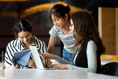 Wallpaper Mural Group of young women working together with laptop and tablet in a modern workspace, discussing ideas, learning, and collaborating on digital projects, representing teamwork, education, and technology Torontodigital.ca