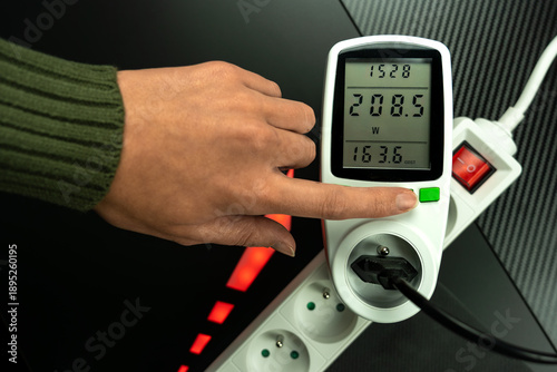 Slika na platnu hand pointing at wattmeter, device that helps monitor electricity consumption (in watts)