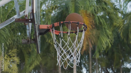 Slow motion of a basketball falling through the hoop in an outdoor park