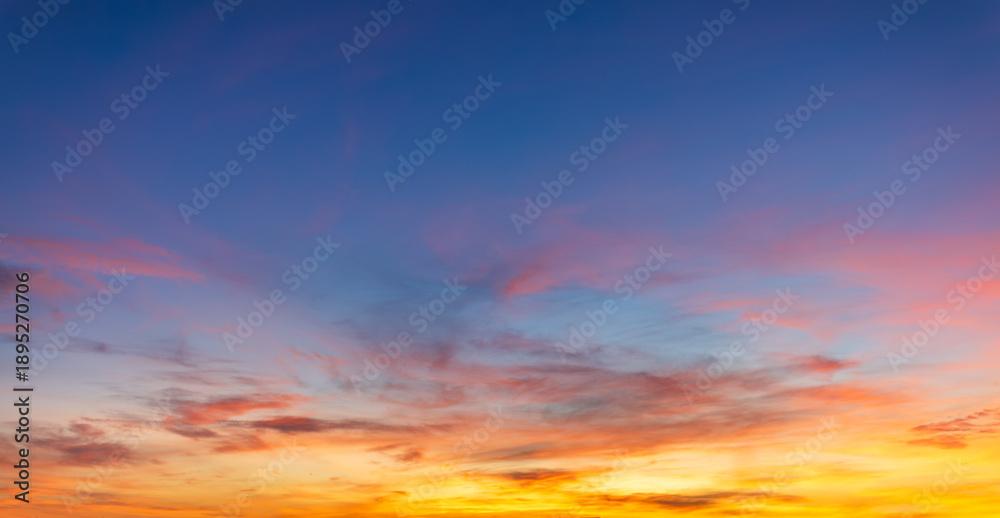 Fototapeta premium Beautiful sunset sky with colorful pink and orange clouds at twilight background,Spectacular sunset sky featuring soft wispy clouds in vibrant shades of pink, orange, and blue. A serene and peaceful.