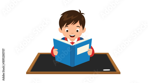 Diligent young boy sitting at a desk and reading an open blue book with focused attention and a happy expression.